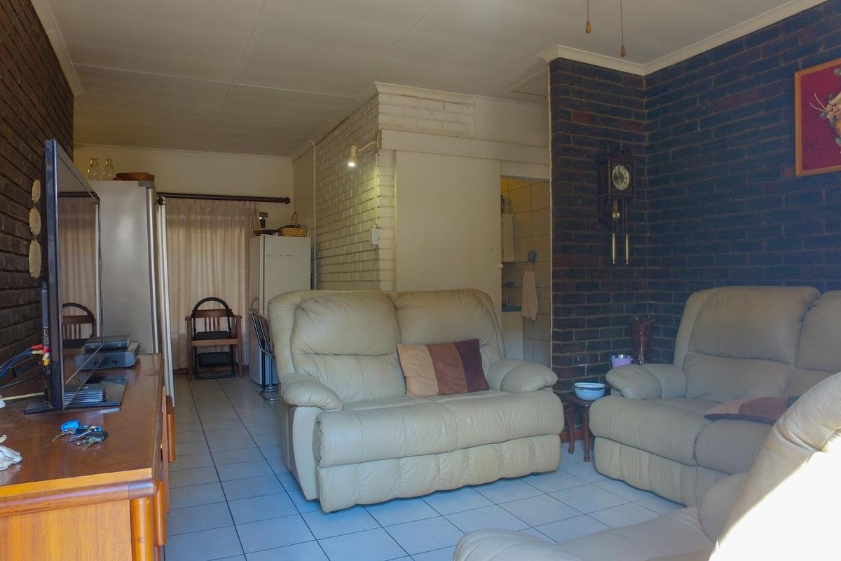 A living room featuring exposed brick walls and tiled flooring, offering a dated aesthetic that could benefit from modern updates.
