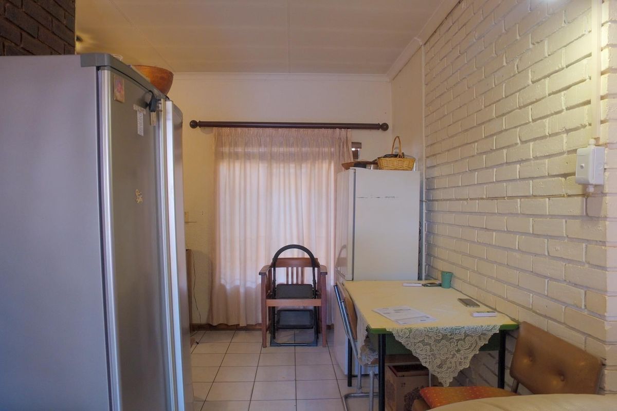 A functional kitchen area featuring tiled flooring and a painted brick feature wall, providing a neutral base for potential updates.
