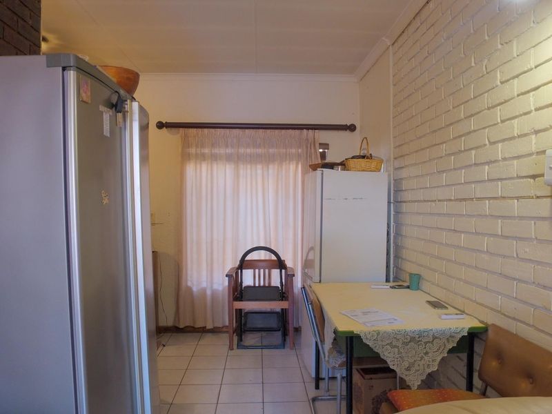 A functional kitchen area featuring tiled flooring and a painted brick feature wall, providing a neutral base for potential updates.