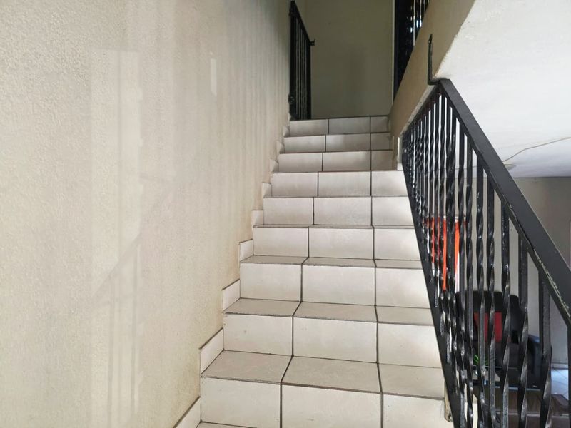 A functional staircase featuring tiled steps and a black wrought iron balustrade, providing access between levels in the townhouse.