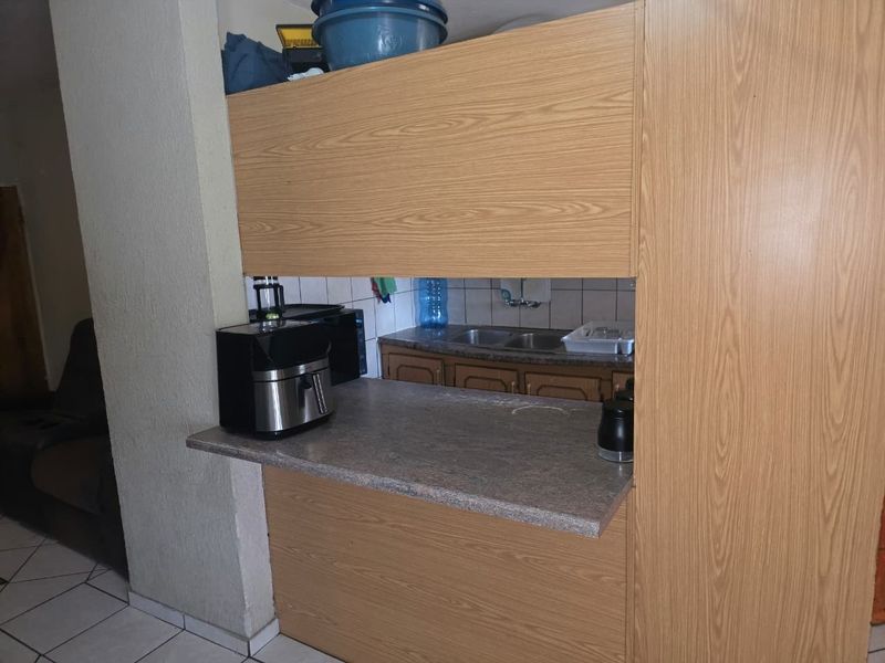 A compact kitchen featuring laminate cabinetry, a breakfast bar, and a double bowl sink with a tiled backsplash.