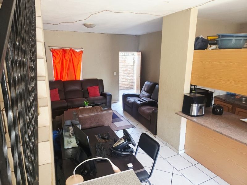 Open-plan living area featuring tiled flooring, a functional kitchen with built-in cabinetry, and direct access to an outdoor space.