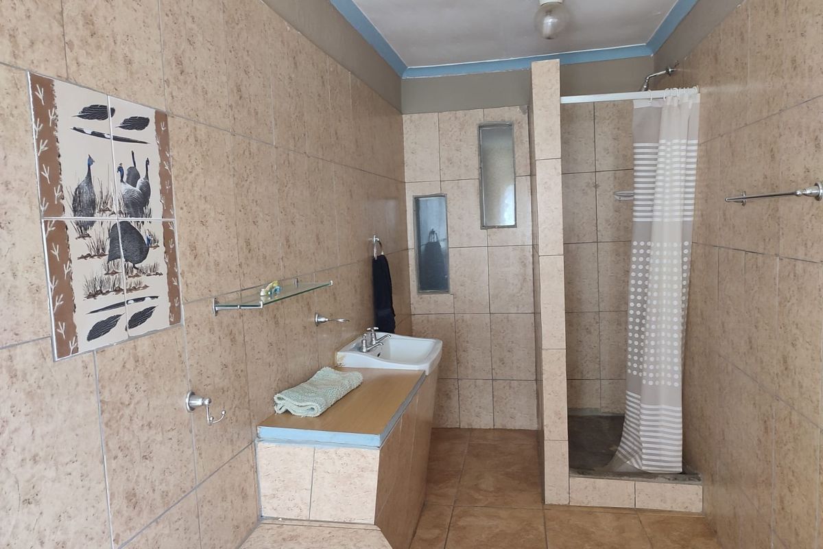 A functional bathroom featuring a walk-in shower, tiled walls and flooring, and a built-in vanity basin with storage counter.