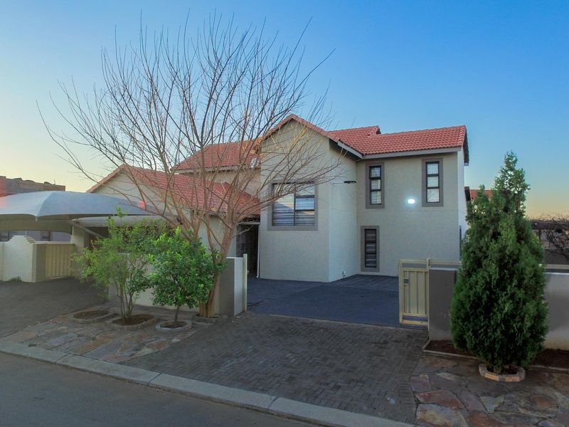 Front elevation of a double-storey house featuring a tiled roof, paved driveway, and a covered carport area.
