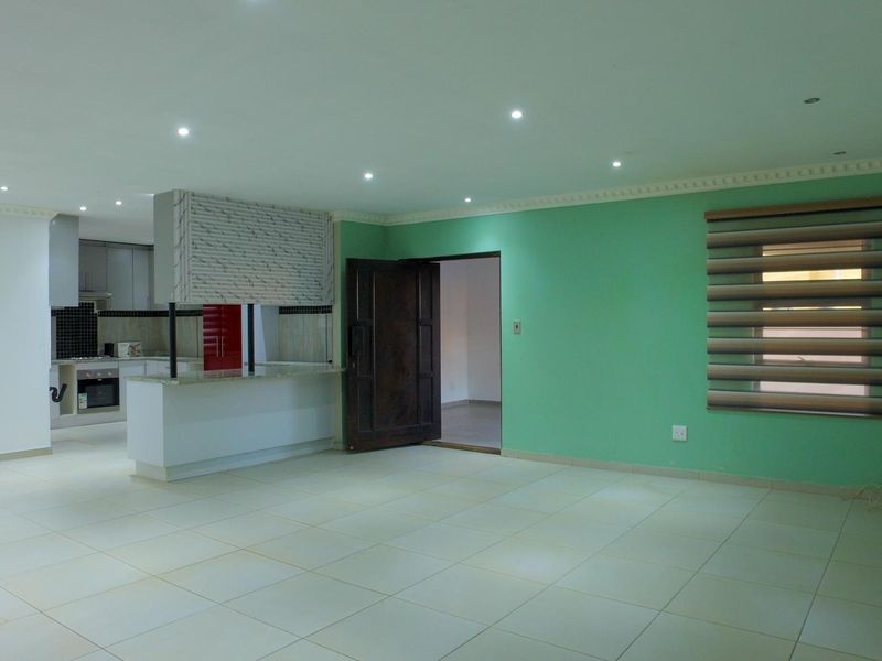 Spacious open-plan living area featuring tiled floors, recessed lighting, and a modern kitchen with built-in appliances and a breakfast island.