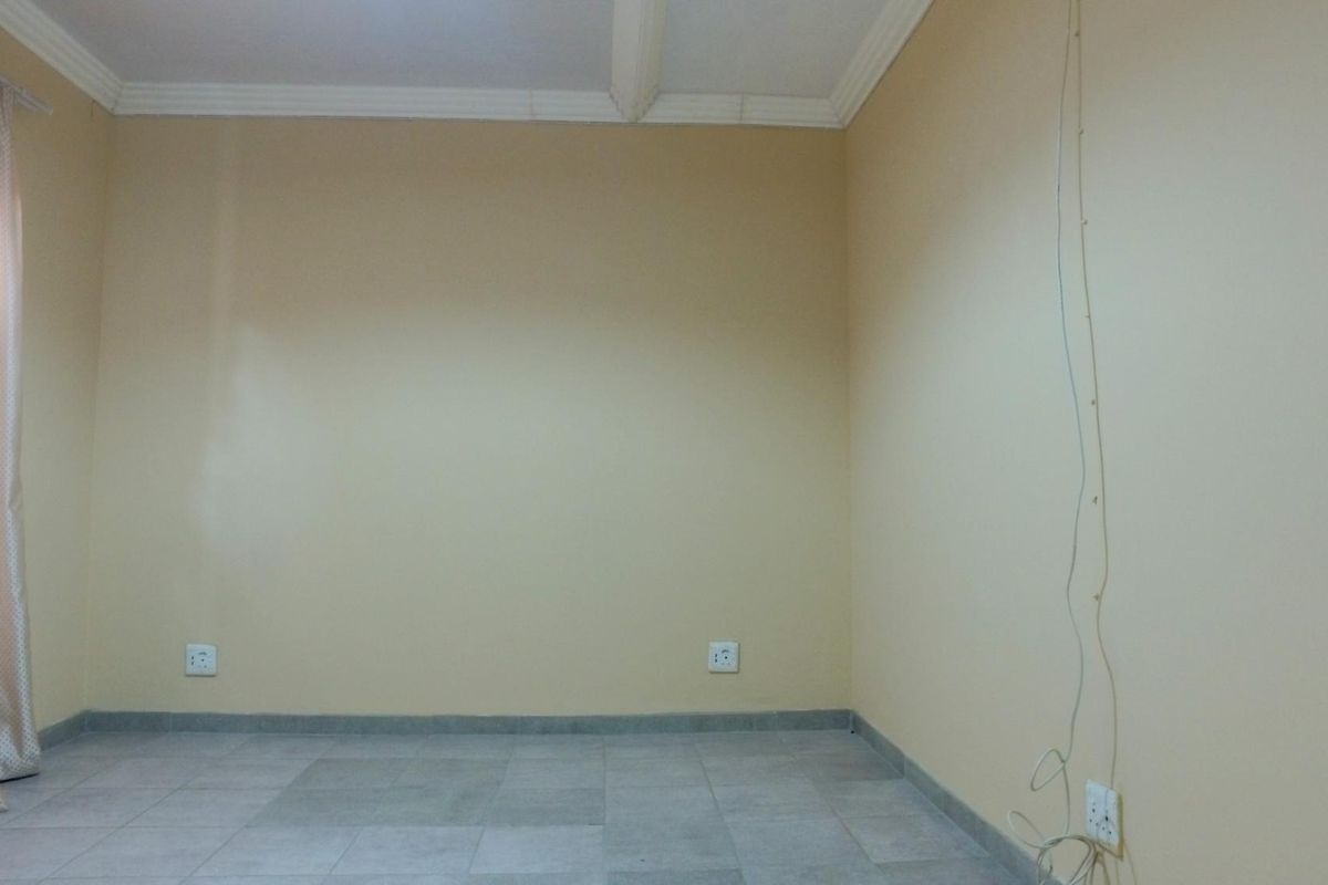 An empty bedroom featuring neutral wall paint, tiled flooring, and crown molding, providing a blank canvas for personalization.