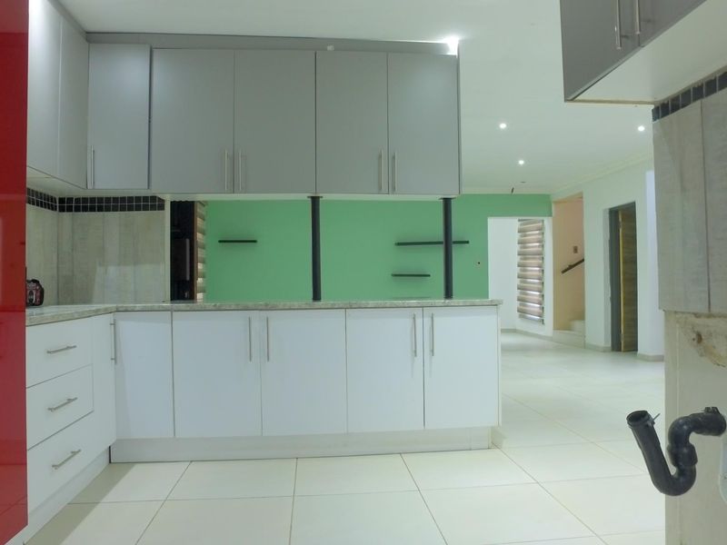 An unfinished kitchen space featuring modern cabinetry, stone countertops, and tiled flooring, currently requiring completion of plumbing and wall finishes.