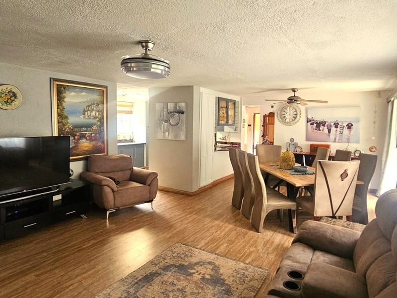 Spacious open-plan living and dining area featuring laminate flooring, ceiling fans, and neutral wall finishes, providing a versatile layout for family living.