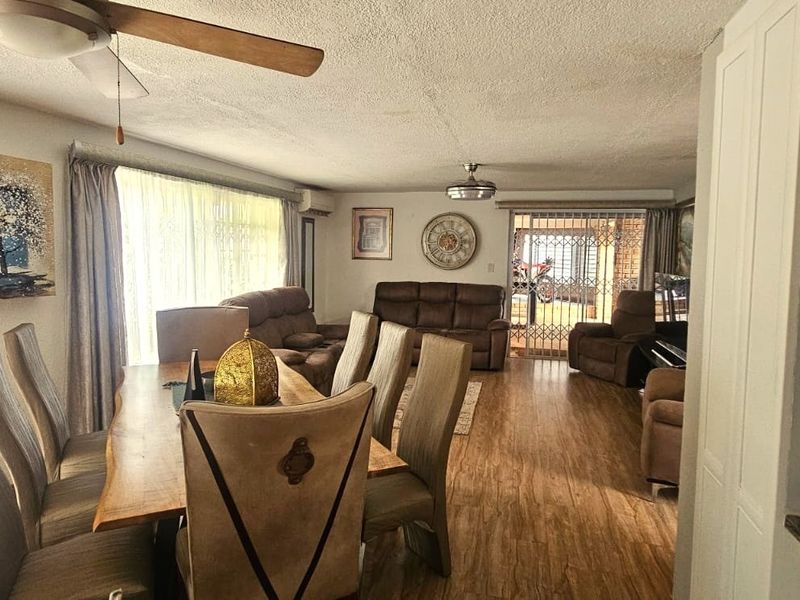 Spacious open-plan living and dining area featuring laminate flooring, ceiling fans, and sliding glass doors leading to an outdoor space.