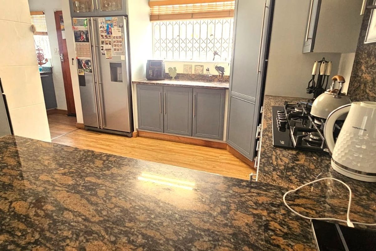 A functional kitchen featuring granite countertops, ample built-in cabinetry, and a gas hob, providing a practical workspace for cooking and meal preparation.