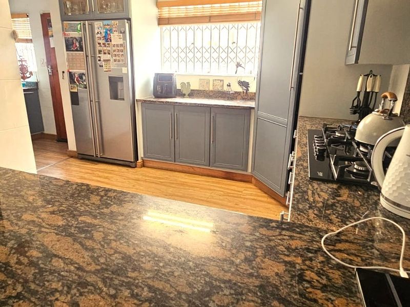 A functional kitchen featuring granite countertops, ample built-in cabinetry, and a gas hob, providing a practical workspace for cooking and meal preparation.