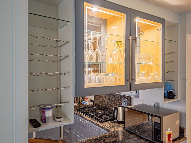 A well-appointed kitchen area featuring granite countertops, a gas hob, and custom cabinetry with integrated display lighting and built-in wine storage.