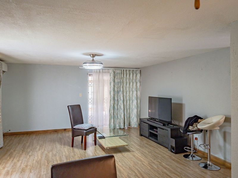 A living room featuring laminate flooring, a ceiling fan, and a sliding glass door providing access to the exterior.