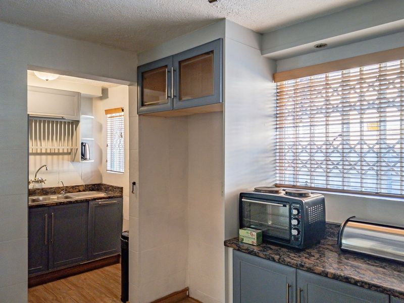A functional kitchen featuring granite countertops, built-in cabinetry, and a secondary scullery area with a sink, offering practical workspace and storage.