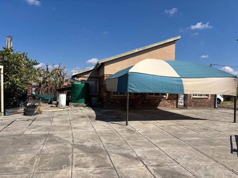 Rear exterior view of the property featuring a large paved patio area, brick facade, and a water storage tank.