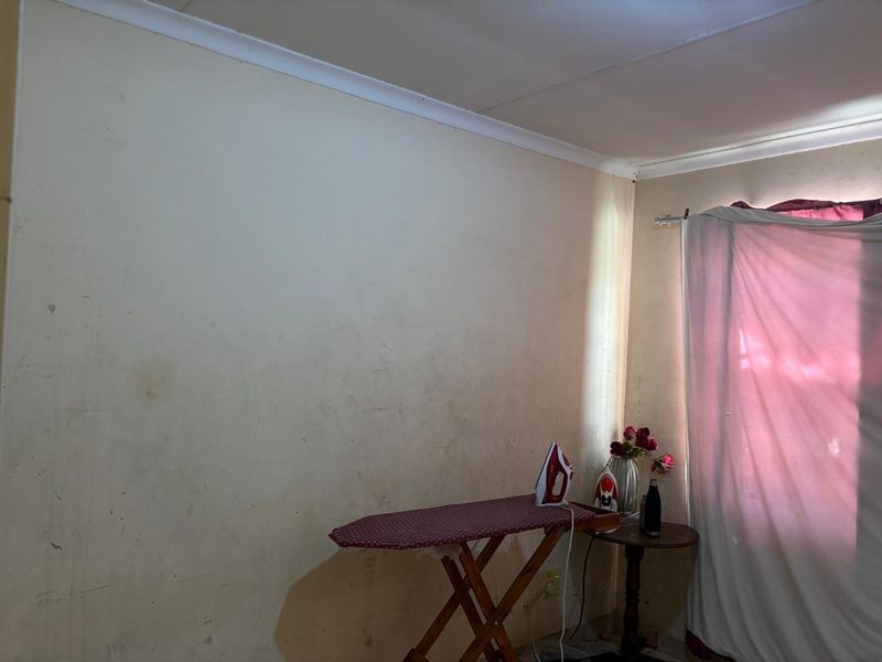 A bedroom interior featuring plain walls with visible staining and scuff marks, requiring cosmetic attention and repainting to improve the overall condition.