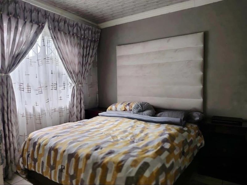A bedroom featuring a large upholstered headboard, textured ceiling, and decorative molding, providing a comfortable and functional sleeping space.