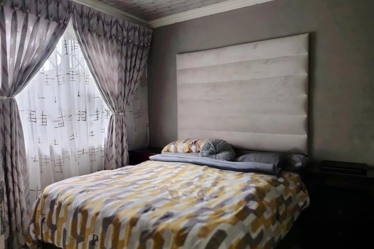 A bedroom featuring a large upholstered headboard, textured ceiling, and decorative molding, providing a comfortable and functional sleeping space.
