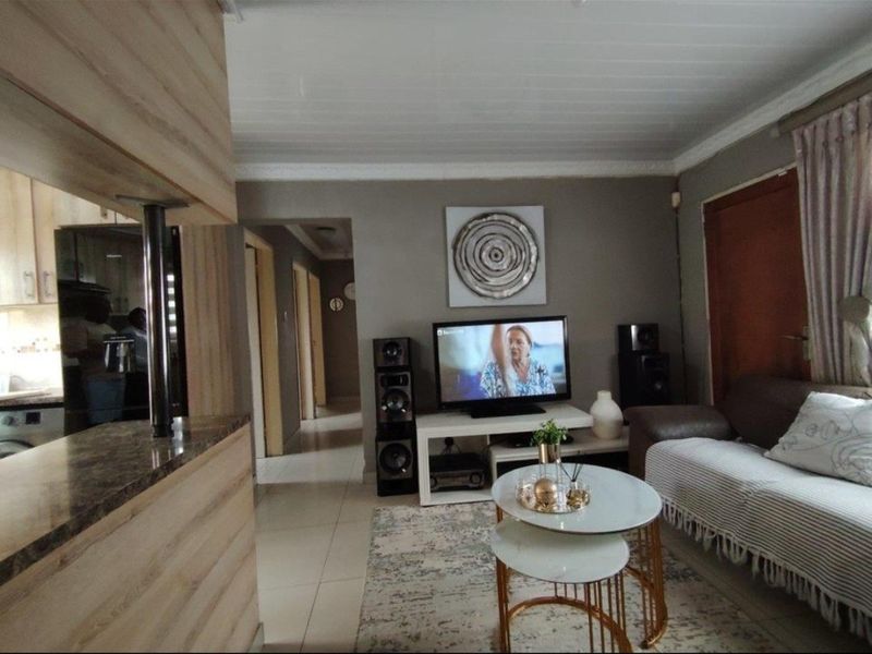 Open plan living area featuring tiled flooring, a breakfast bar, and coved ceilings, providing a functional and connected space for daily living.