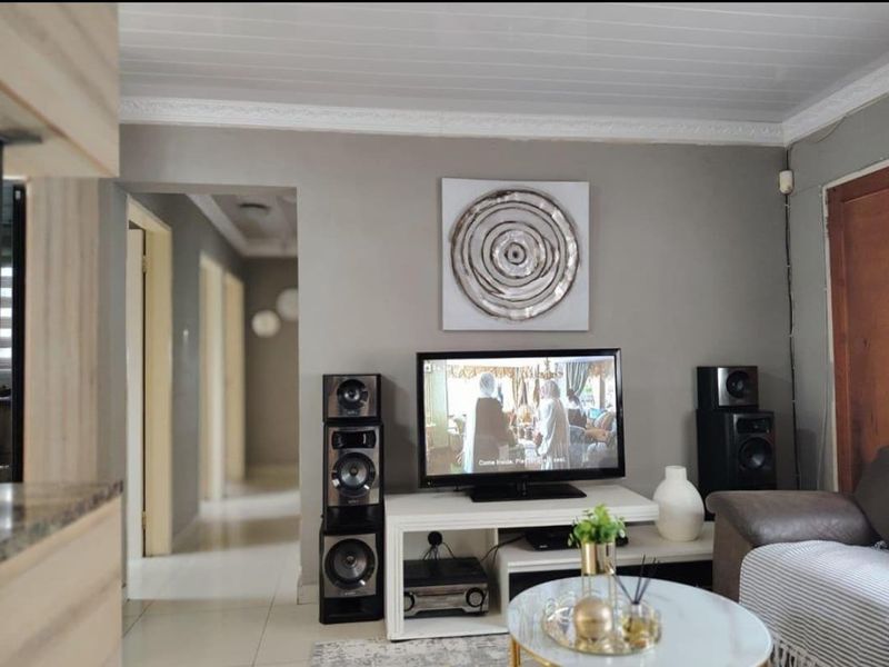 A well-maintained living room featuring neutral wall tones, tiled flooring, and a coved ceiling, providing a comfortable and functional space.