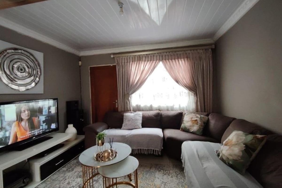 A cozy living room featuring a tongue and groove ceiling with decorative cornice and window curtain rails.