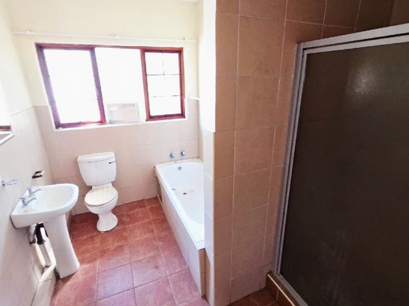 A functional bathroom featuring a pedestal basin, toilet, bathtub, and a separate shower enclosure with tiled finishes throughout.
