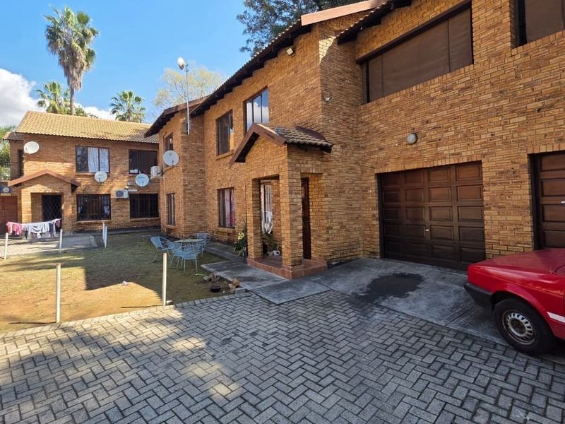 Front view of a face brick apartment complex featuring a paved driveway, garage access, and a covered entrance porch.