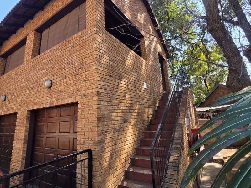 Exterior view of a face brick apartment building featuring a ground-level garage and an external staircase leading to the upper level.