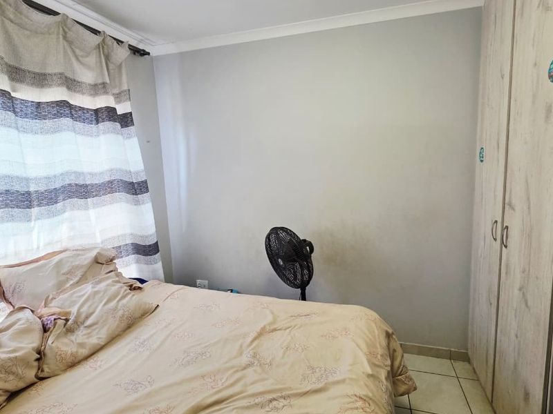 A bedroom featuring tiled flooring and a built-in wardrobe, with visible wall staining requiring attention.