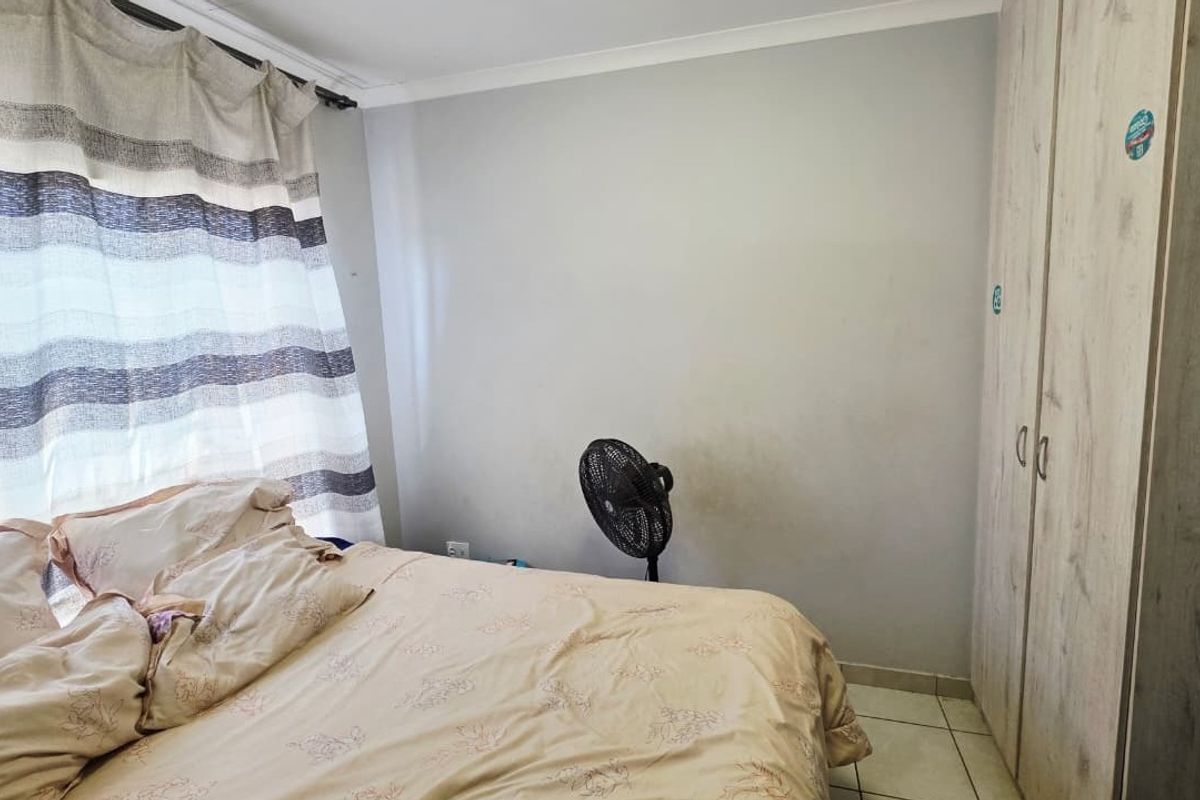 A bedroom featuring tiled flooring and a built-in wardrobe, with visible wall staining requiring attention.