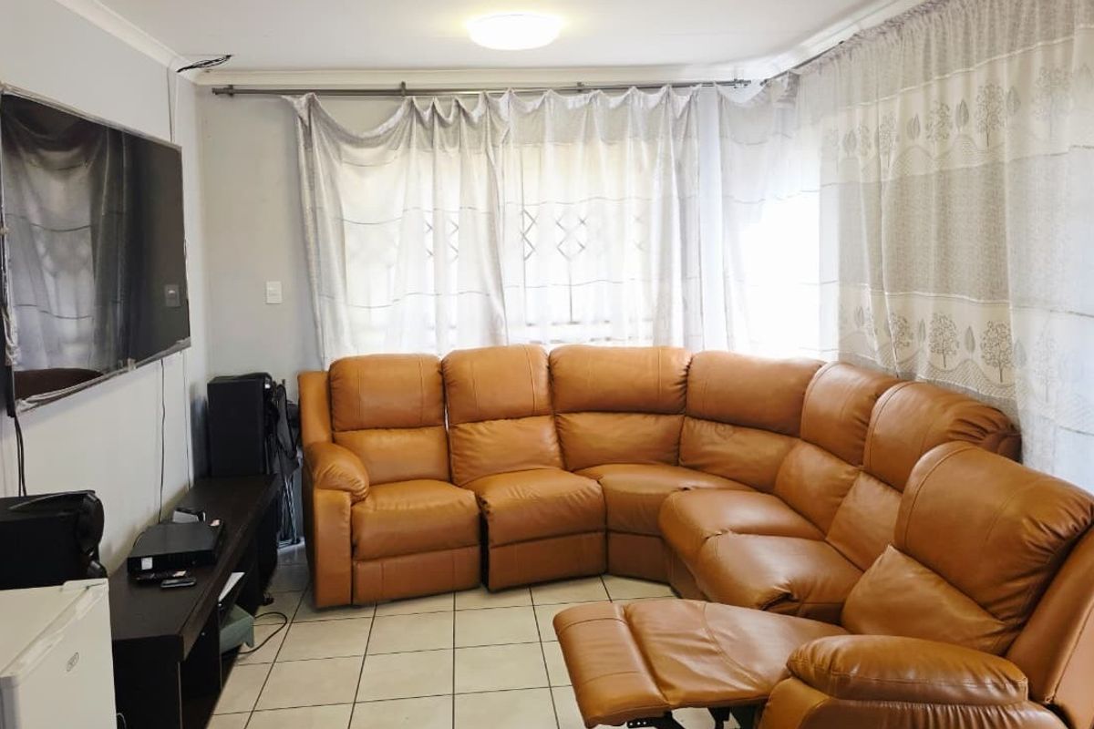 A functional living room featuring tiled flooring and neutral wall finishes, providing a comfortable space for relaxation.
