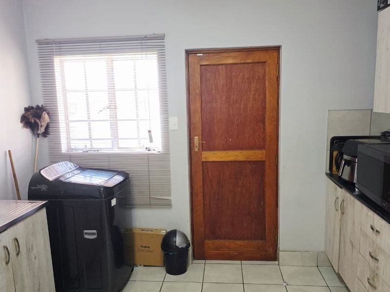 A functional kitchen area featuring built-in cabinetry, tiled flooring, and a window with venetian blinds, providing a practical workspace.