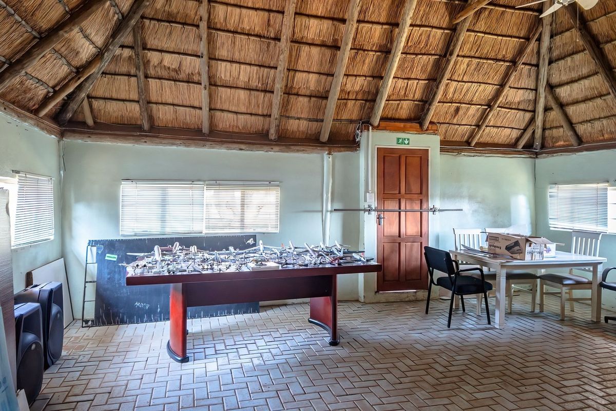 Spacious living area featuring a traditional thatched roof with exposed timber rafters, brick paver flooring, and natural light through multiple windows.