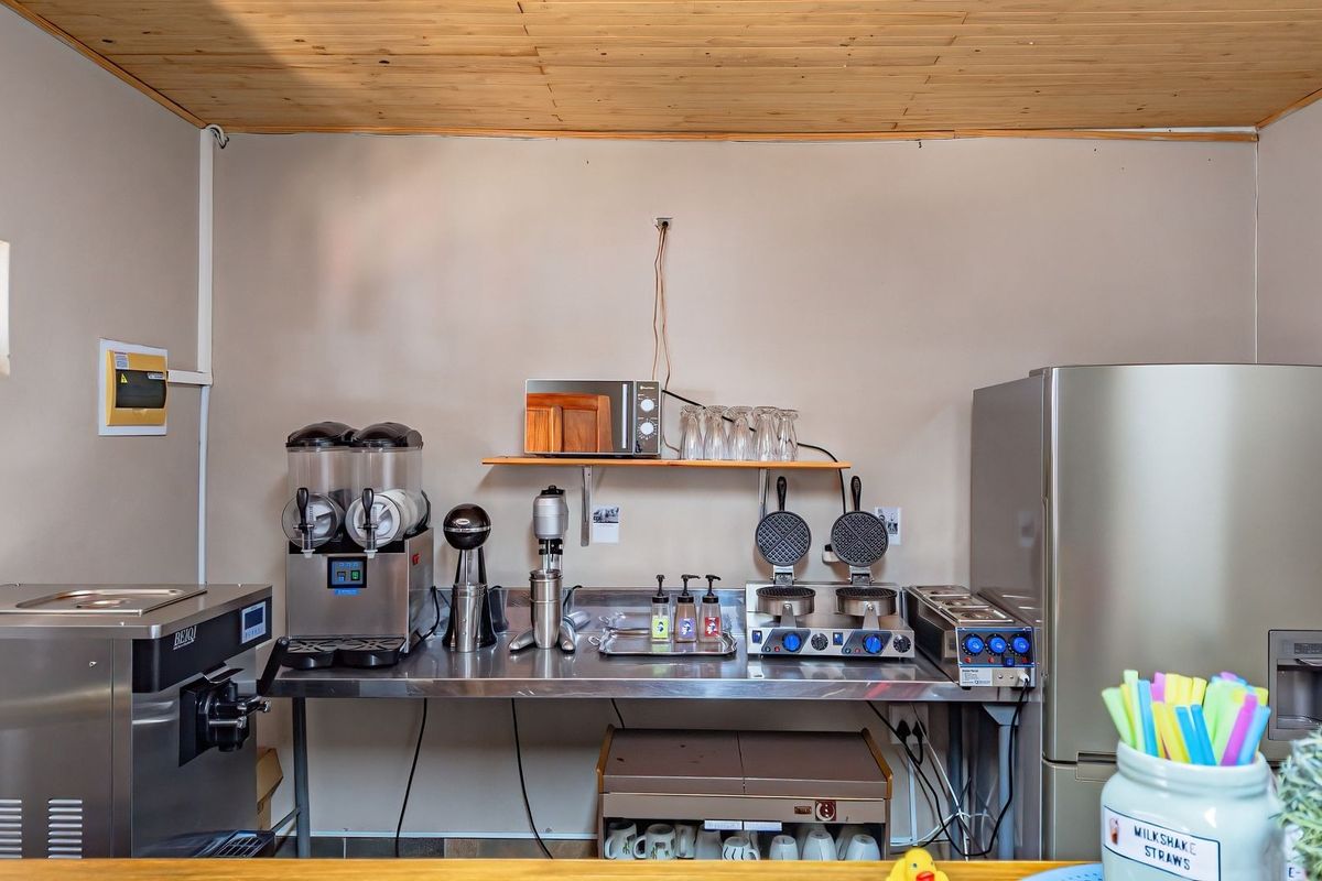 A functional commercial-style kitchen prep area featuring stainless steel surfaces and timber ceiling finishes, suitable for food preparation and service.