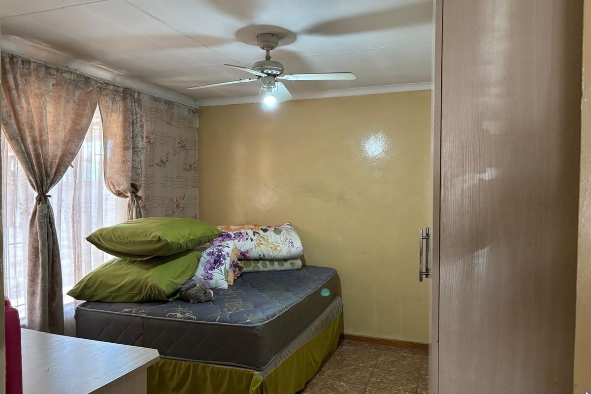 A bedroom featuring a ceiling fan, tiled flooring, and a built-in wardrobe, requiring cosmetic updates to the wall finishes.
