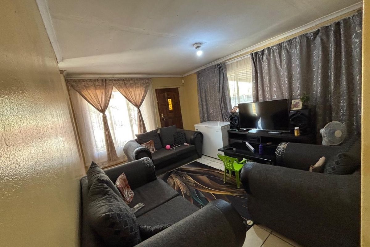 A living room featuring tiled flooring, a timber entrance door, and coved ceilings, requiring cosmetic updates to improve the overall aesthetic.