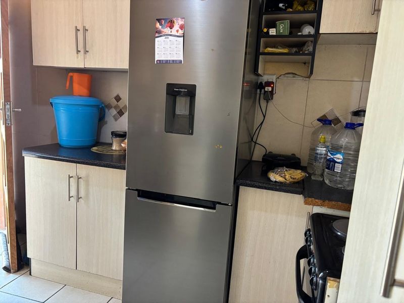 A functional kitchen featuring laminate cabinetry, dark countertops, and tiled backsplash, offering a practical layout for daily meal preparation.