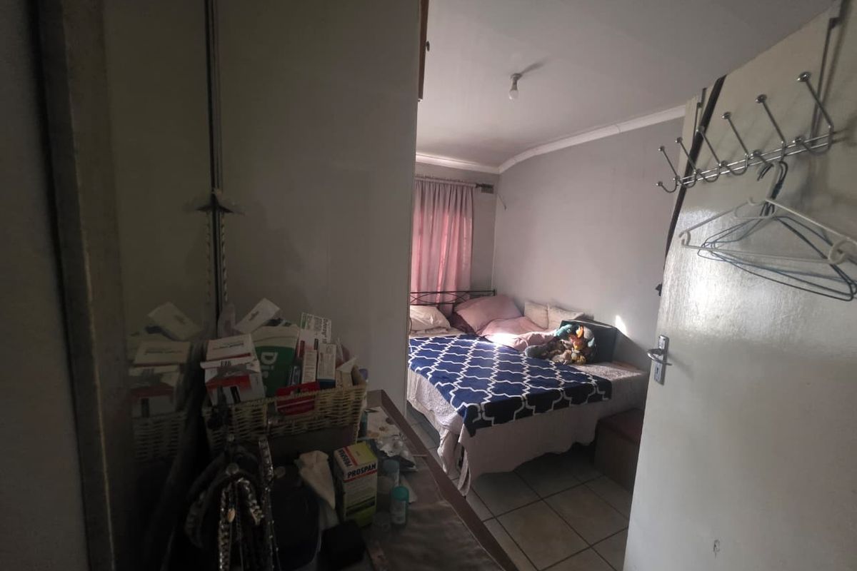 A bedroom featuring tiled flooring and natural light, viewed from an adjacent space through a doorway.