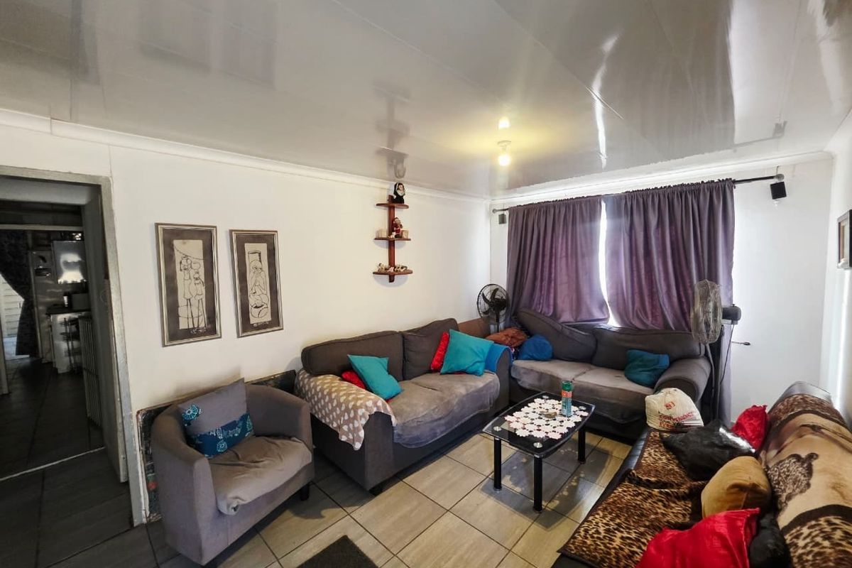 A living room featuring tiled flooring and a glossy ceiling finish, providing a functional space with direct access to an adjacent room.