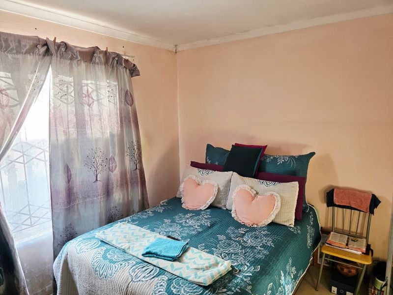 A bedroom featuring a window with a security gate and coving detail, currently requiring cosmetic updates to the wall finishes.