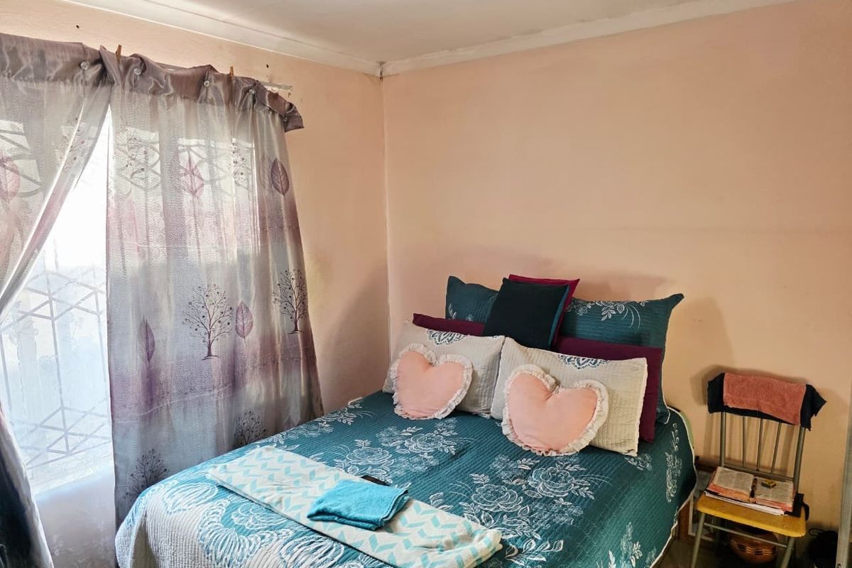 A bedroom featuring a window with a security gate and coving detail, currently requiring cosmetic updates to the wall finishes.