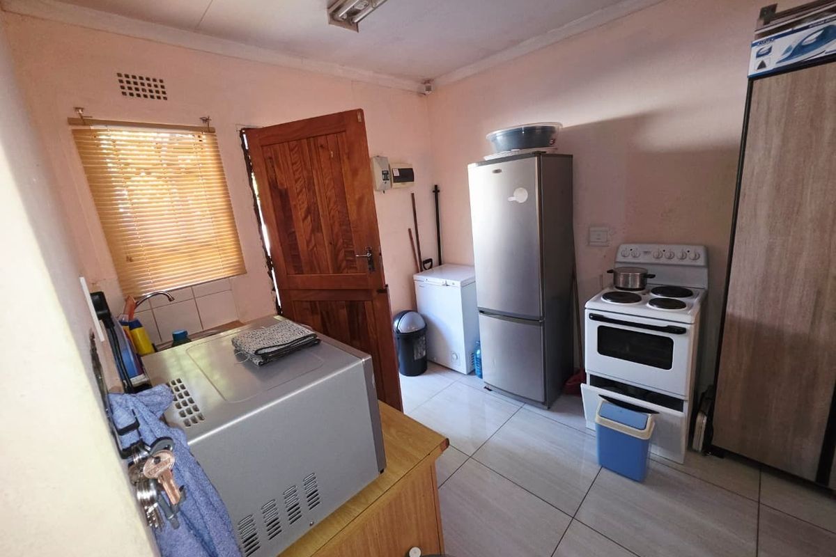 A functional kitchen space featuring tiled flooring, a built-in sink, and timber door access, offering potential for modernization and aesthetic updates.