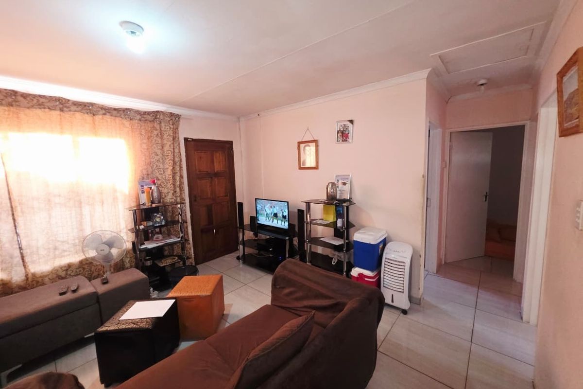 A living room featuring tiled flooring and coved ceilings, providing a functional space with potential for cosmetic updates to enhance its overall appeal.