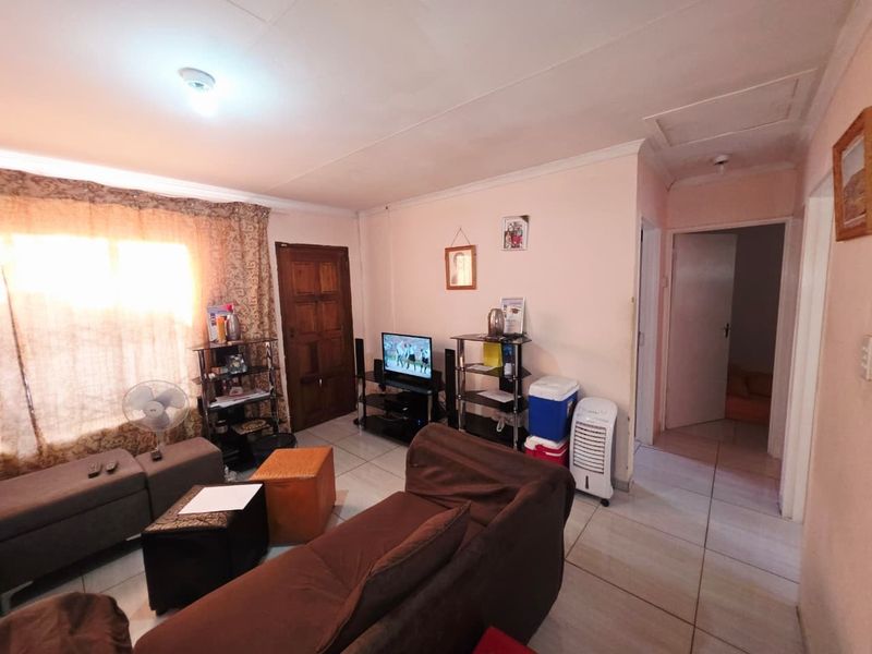 A living room featuring tiled flooring and coved ceilings, providing a functional space with potential for cosmetic updates to enhance its overall appeal.