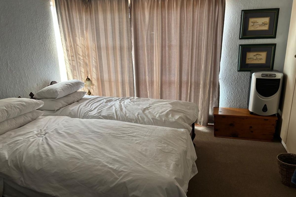 A functional bedroom featuring carpeted flooring, a built-in wardrobe, and a large sliding glass door providing natural light.
