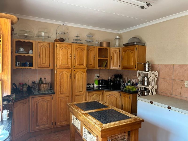 A dated kitchen featuring traditional wooden cabinetry, tiled backsplash, and tiled flooring, offering a functional layout with potential for modern renovation.