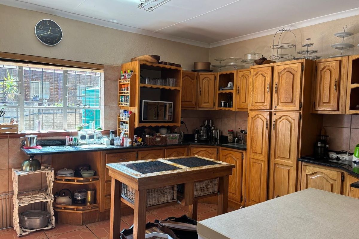 A traditional kitchen featuring extensive wooden cabinetry, laminate countertops, and tiled flooring, offering a functional layout with ample storage space.
