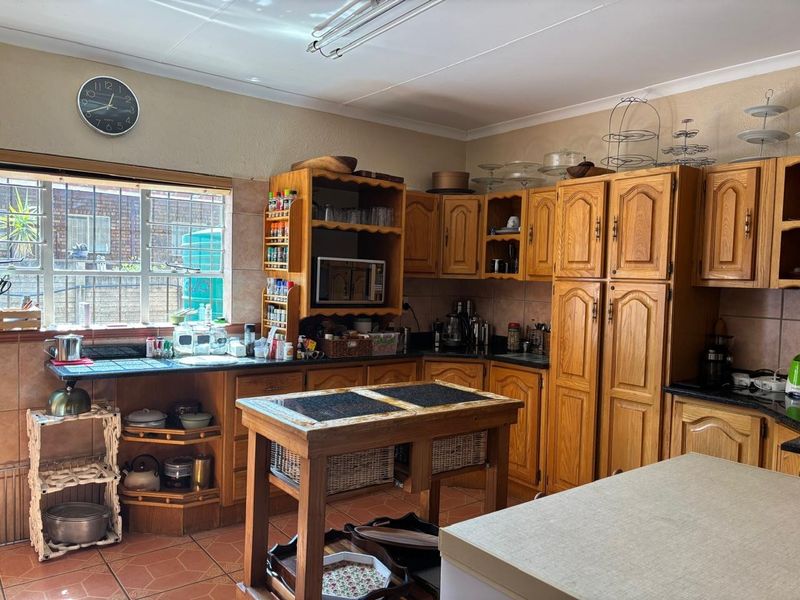 A traditional kitchen featuring extensive wooden cabinetry, laminate countertops, and tiled flooring, offering a functional layout with ample storage space.