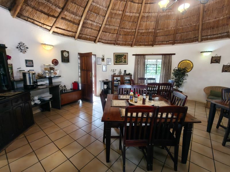 Spacious dining area featuring a traditional thatched roof with exposed rafters and ceramic tiled flooring, creating a rustic and inviting atmosphere.