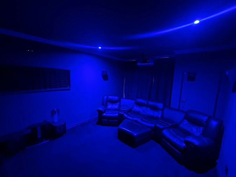 Dedicated cinema room featuring recessed ceiling lighting, projector setup, and acoustic wall treatments for an immersive viewing experience.